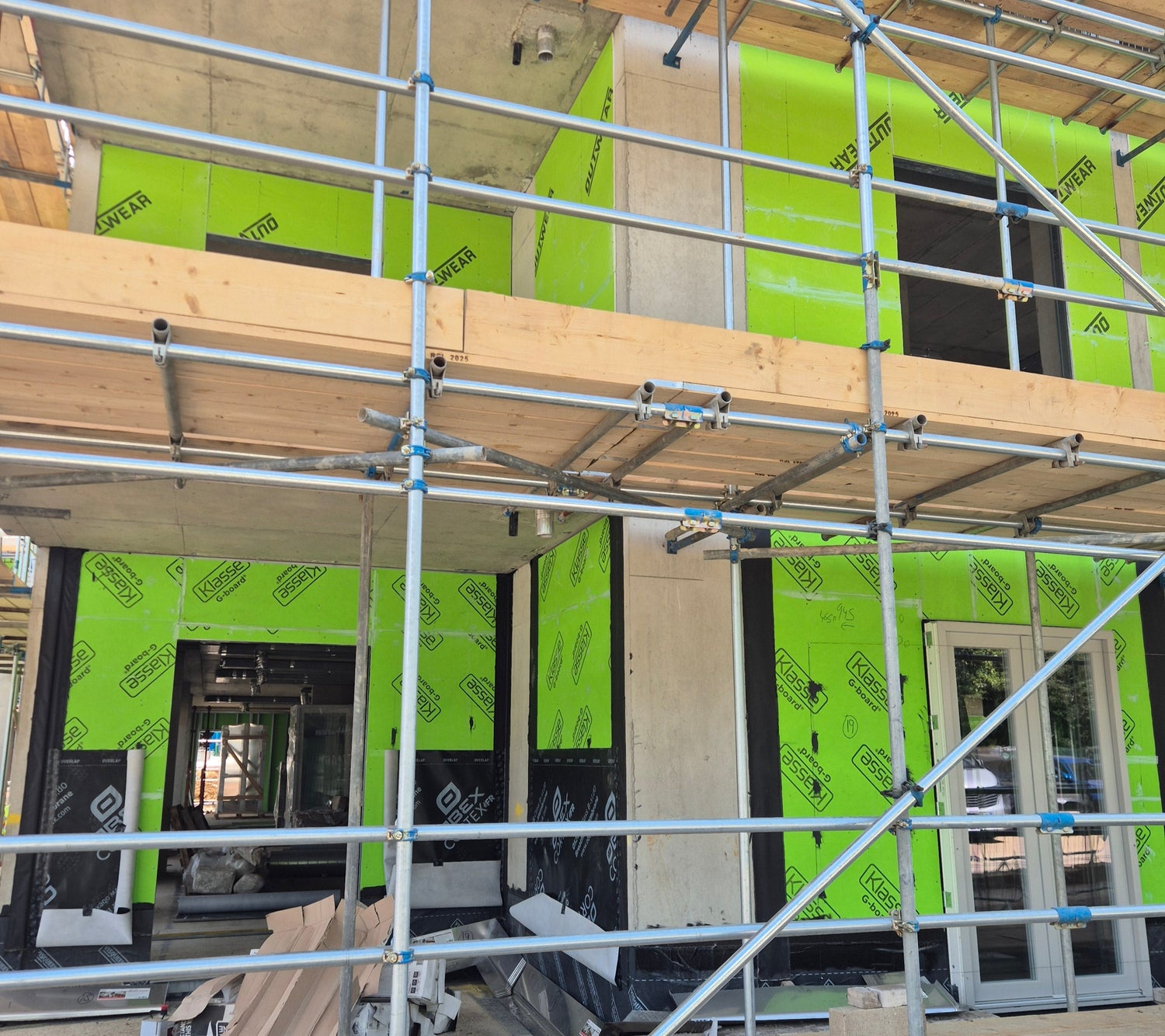 Building under construction with scaffolding and green insulation on the walls.